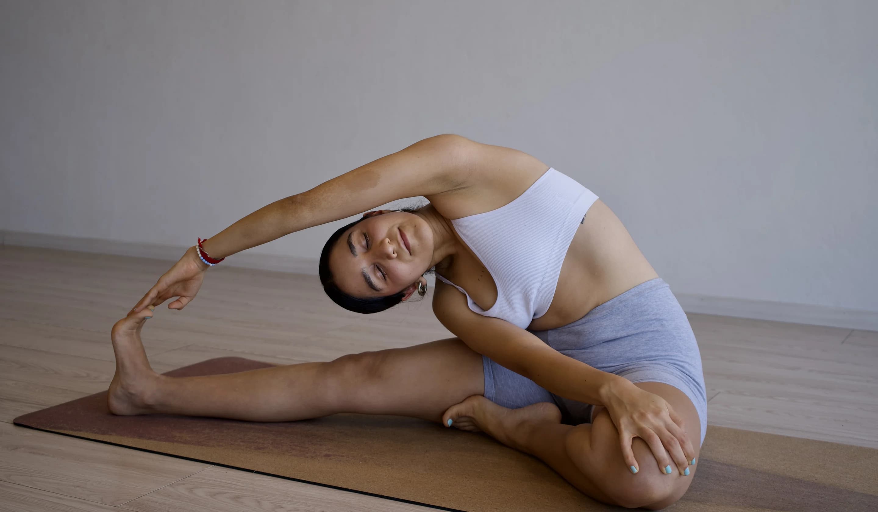 Una estudiante en una flexión lateral sobre su tapete, con el brazo estirado por encima de la cabeza